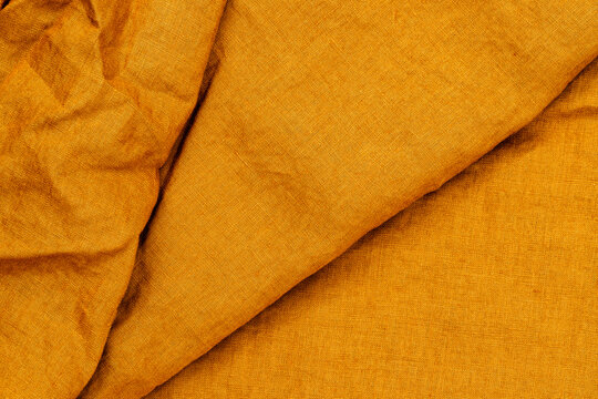 Fabric draped on a surface in a studio setting showcasing rich texture and warm color during daylight hours