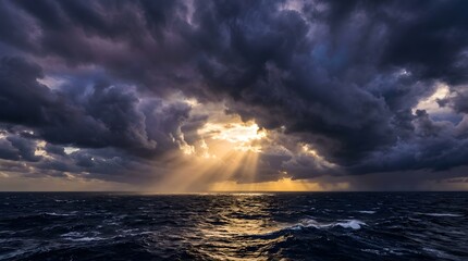 Fototapeta premium Dramatic sunbeams breaking through dark storm clouds over ocean waves.