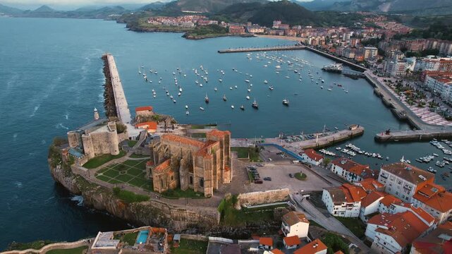 Cinematic drone panoramic aerial footage of Castro Urdiales town in Cantabria Spain. historic architecture and surrounding hills during golden hour light. High quality 4k footage