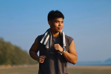Fototapeta premium Young Asian man jogging on the beach in the morning light.