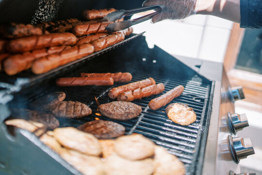 Barbecue feast scene. Cooking on charcoal grill. Juicy grilled sausages and burgers at summer gathering