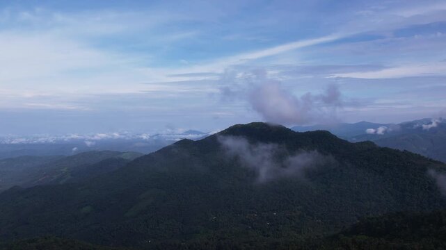 Aerial drone view of lush green mountain hills under dramatic cloudy sky 