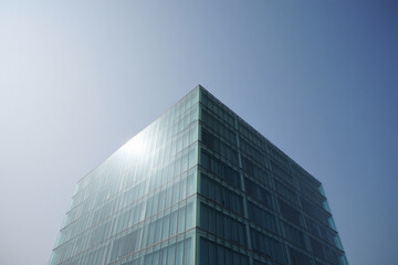 Obraz premium Modern glass building corner against bright blue sky
