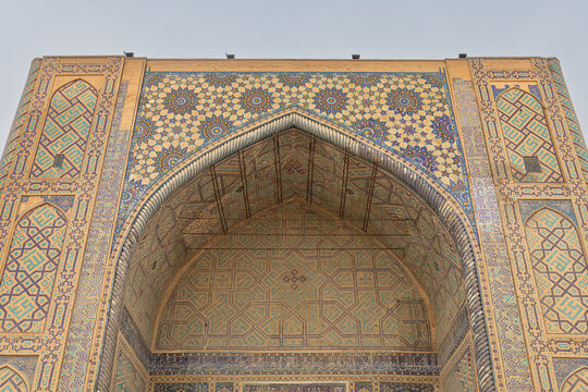 Ulugbek Madrasah Portal in Registan Complex, large decorative iwan arch covered in intricate geometric mosaic tiles and calligraphic panels