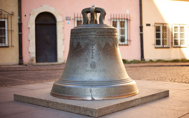Obraz premium The Wishing Bell in Warsaw Old Town: Historic Bronze Bell on Kanonia Street, Polish Landmark and Cultural Heritage Monument with Ornate Reliefs under Soft Daylight