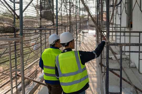 Construction workers inspecting scaffolding installation construction site image urban environment close-up view safety compliance