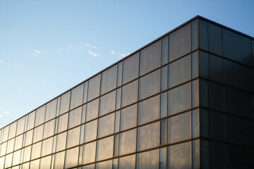 Fototapeta premium Modern glass building corner against blue sky with white clouds