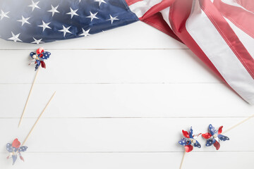 Obraz premium Red, white, and blue pinwheels and United States Flag on a white, wooden surface with space for message text. American Memorial, Independence, Labor, or Veteran's Day background.