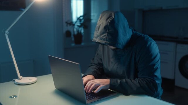 Medium Shot One Hacker In Hoodie Thinking And Typing On Laptop