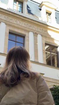 Young woman gazes at decorative facade elements with admiration