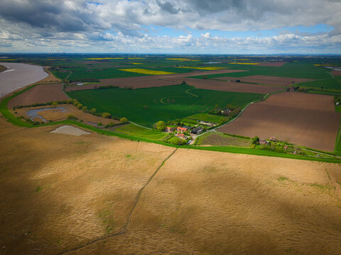 Aerial view of Trent Falls showing the confluence of the River Ouse and River Trent surrounded by vast agricultural fields and rural farmhouses under a cloudy sky in Goole, United Kingdom.