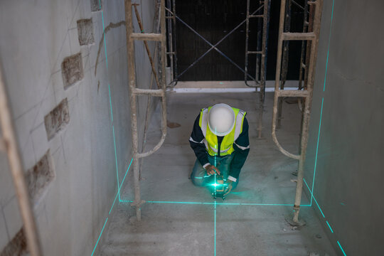 Construction worker using laser level for measurements indoor site professional work industrial environment close-up view