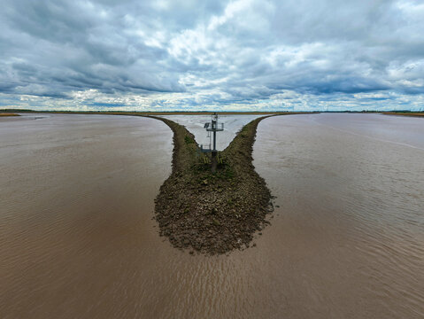 Aerial view of Trent Falls confluence with the stone breakwater and navigation beacon under an overcast sky in Goole, United Kingdom.