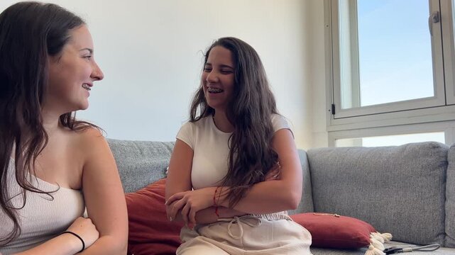 Paneo de dos chicas con brackets hablando y riendo en el sof&aacute;