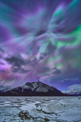Northern Lights Over Frozen Lake and Snowy Mountains in Winter Nightscape