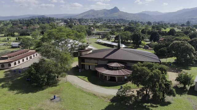 Drone flies west over Eswatini National Church and King Sobhuza II Park toward fairgrounds on sunny morning in Lobamba, Eswatini