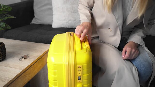 Stylish woman in trench coat leaves home with yellow suitcase, leaving keys on table. Concept of lifestyle change, independence, personal growth, and starting new chapter in life.