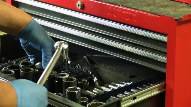 Close-up of hand selecting a large socket and extension from a metal tool chest drawer in a garage workspace. Mechanic tool selection process, automotive repair preparation, organized tool storage, wo