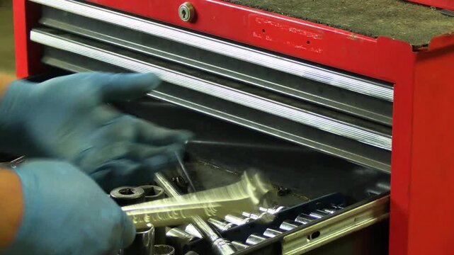 Hand grabbing a wrench from a tool chest drawer and slapping it into the palm, preparing for mechanical work. Garage environment, mechanic tools, automotive repair preparation, workshop action shot, t