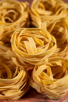 Dry egg pasta shaped in nests on a tile surface 