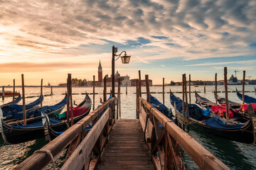 Iconic wooden pier with Venetian gondola on Grand Canal and famous church in Venice © Mumemories