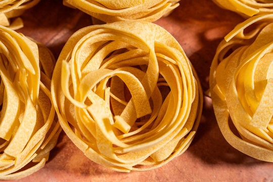 Dry egg pasta shaped in nests on a tile surface 