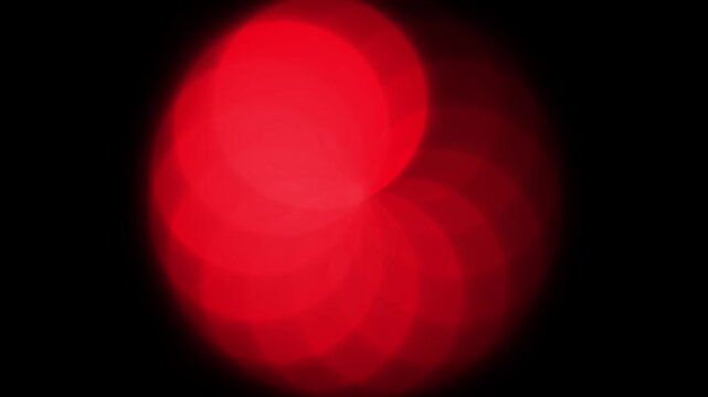 Abstract red glowing flower light pattern on black background with soft blur and radial symmetry