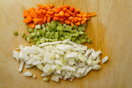 Diced soffritto vegetables on wooden cutting board top view