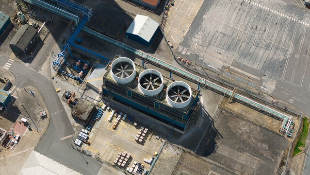 Aerial view of three large industrial cooling fans and blue pipeline infrastructure at the Salt End chemical park Salt End, England, United Kingdom.