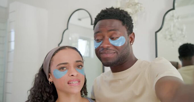 African American couple holding phone at vanity adjusting blue undereye patches to capture moment