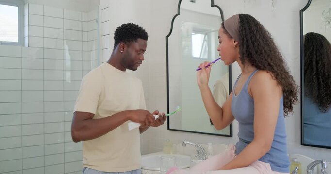 African American couple during morning routine, man squeezing paste onto brush while both brushing