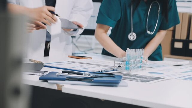 A vibrant red anatomical heart model and a stethoscope on a desk with two doctors having a medical consultation in the background.