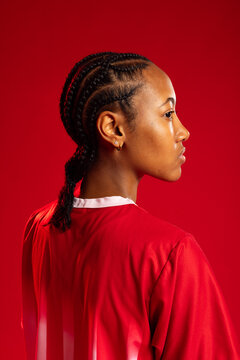 African American woman posing in studio, red jersey white collar showing cornrow braids, gold hoops