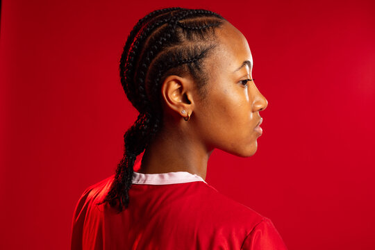 Adult African-American woman studio profile wearing red white-trim shirt braids hoop-stud earrings