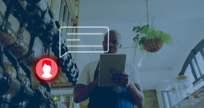 Holding shop owner wearing dark apron checking tablet in retail shop, with labeled jars, UI overlay