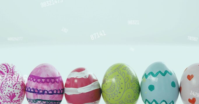 Displaying row of painted glossy eggs on white table with pale blue gradient and faint numbers
