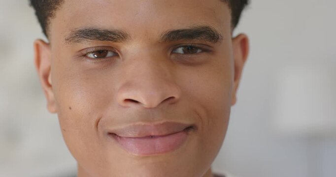 African American teen male holding eyes closed, opening eyes and smiling in bright home, lamp right