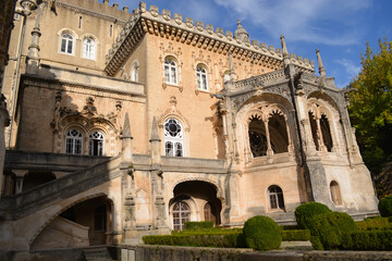 Fototapeta premium Blooming bougainvillea and vegetation in the park in front of the Busaco Palace in Portugal Coimbra region. Themes include travel, cultural heritage, and natural beauty.
