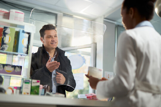 Happy mid adult man  talking to a pharmacist while buying a medicine in a drug store