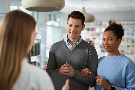 Happy diverse couple consulting female pharmacist while buying a medicine in a pharmacy