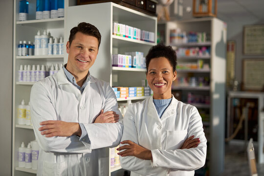 Portrait of happy diverse pharmacists standing in a pharmacy and looking at camera.