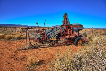 Fototapeta premium Abandoned Farm Equipment in Arizona Desert with Dry Vegetation and Clear Blue Sky