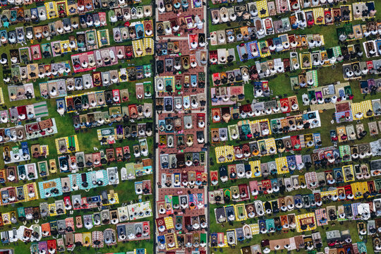 Aerial view of a large group of Muslim people performing communal prayer on colorful mats spread across a green field in Klaten, Jawa Tengah, Indonesia.