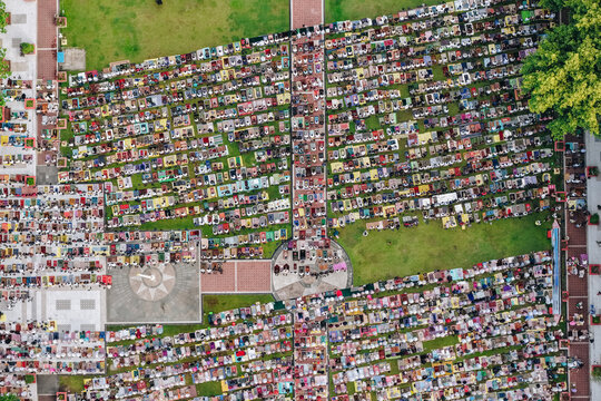 Aerial view of a large crowd of people praying on colorful prayer mats in a public square with a central monument and green lawns Klaten, Jawa Tengah, Indonesia.