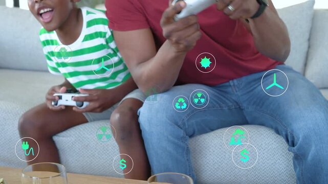 Dad and son pressing gamepads at home, green icons popping over hands as game feedback