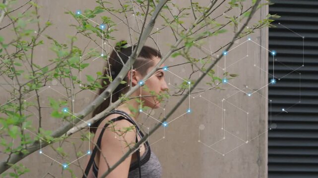 Woman walking along beige wall, passing sapling, nearing vent, activating tech hexagon around head