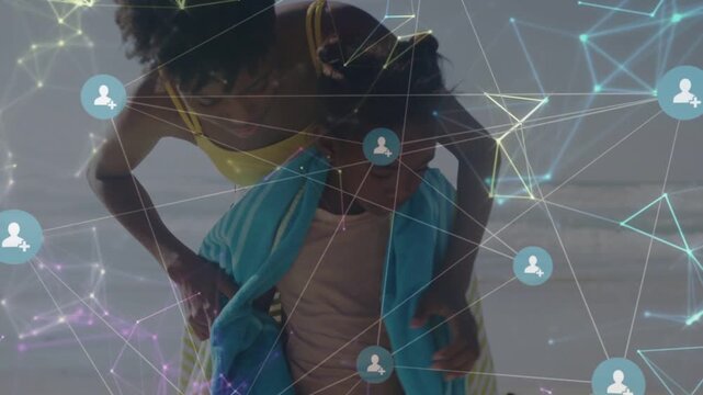 Caregiver leaning forward wrapping child with teal towel on beach, network overlay scene for health