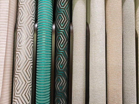 A variety of wallpaper rolls neatly stacked on shelves at a home improvement store, offering a wide selection of designs and patterns for home decor