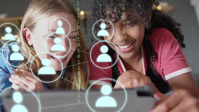 Two teen girls leaning over tablet, one tapping screen exploring growing social avatar network