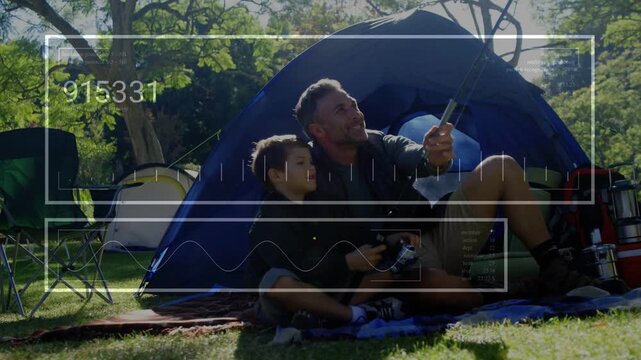 Dad and son sitting blanket camp dad raising pole device causing HUD updating son learning tech